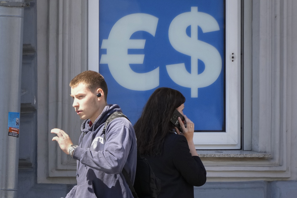 People walk past a currency exchange office in St. Petersburg, Russia, Thursday, June 13, 2024. The U.S sanctioned the Moscow Exchange Wednesday, prompting Russia's biggest stock exchange to halt trades in dollars and euros. AP Photo/Dmitri Lovetsky